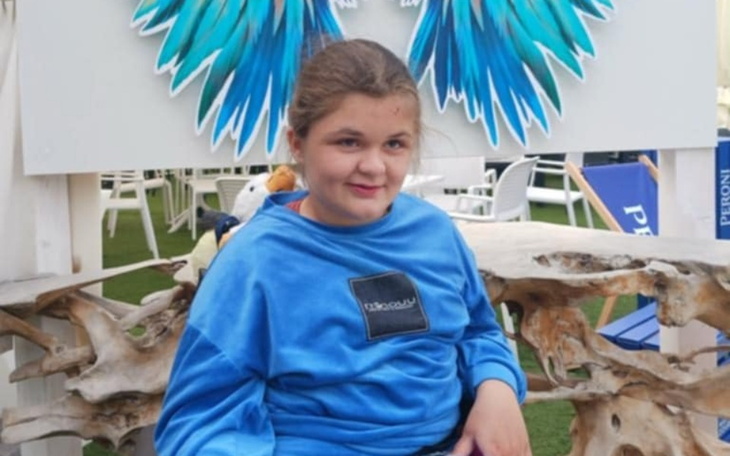 Dziewczynka w niebieskiej bluzie, siedząca na tle skrzydeł.