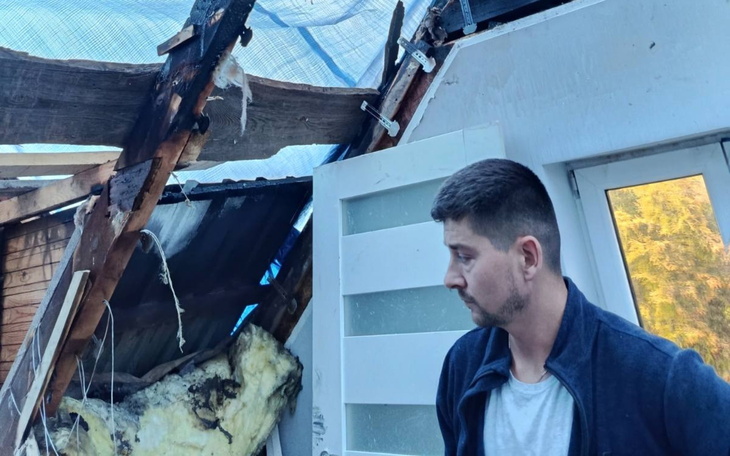 Mężczyzna przy zniszczonym dachu, oceniający szkody.