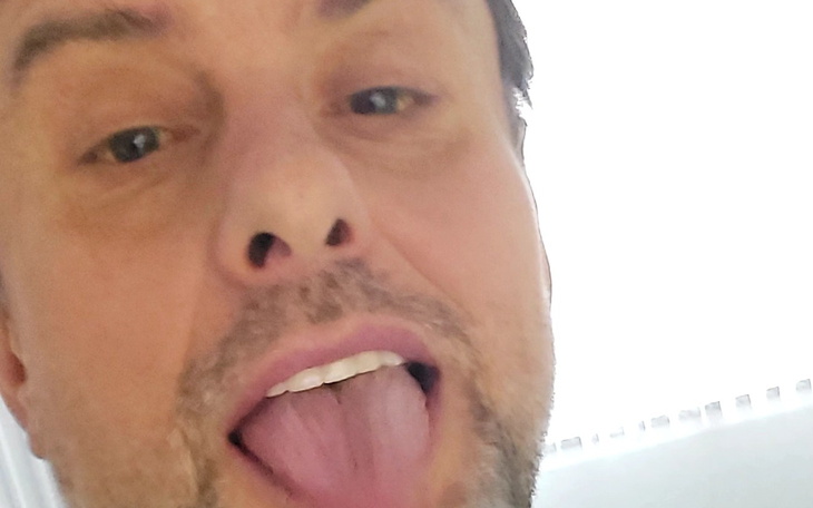 Mężczyzna robiący dziwną minę, pokazujący język.