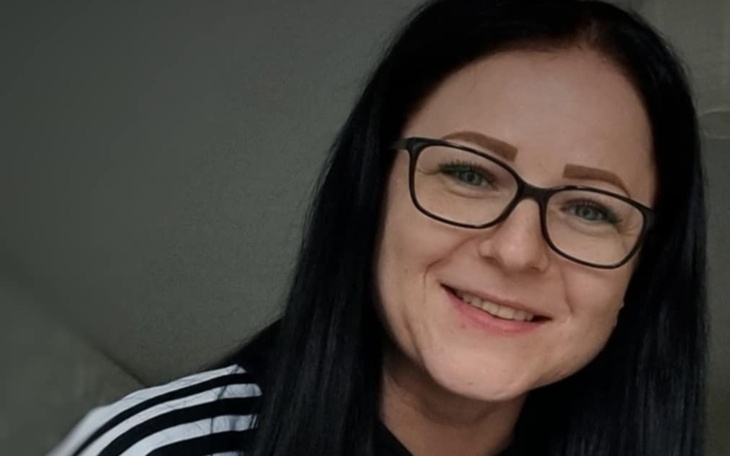 Portret uśmiechniętej kobiety w okularach, z długimi włosami.