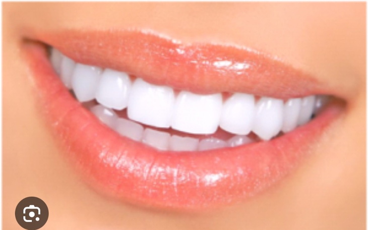 Uśmiech z białymi zębami na tle jasnego koloru.