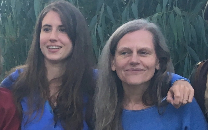 Dwie kobiety pozujące razem w plenerze, uśmiechnięte.