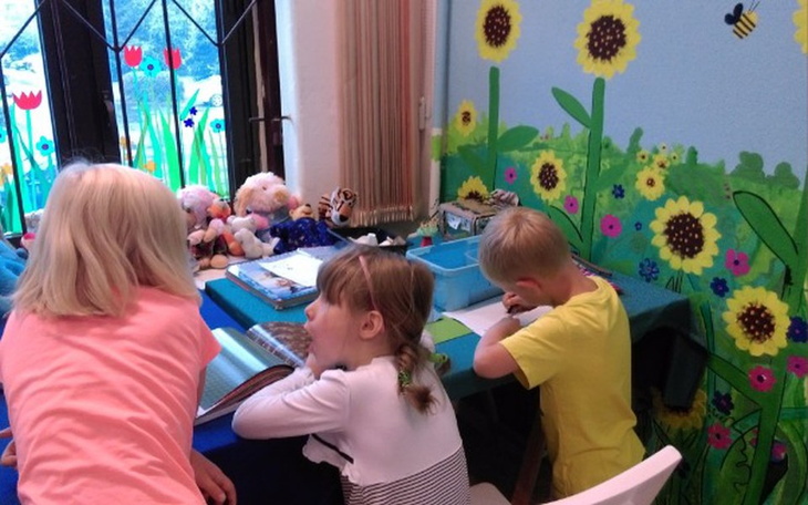 Dzieci rysujące w przytulnym, kolorowym pomieszczeniu.