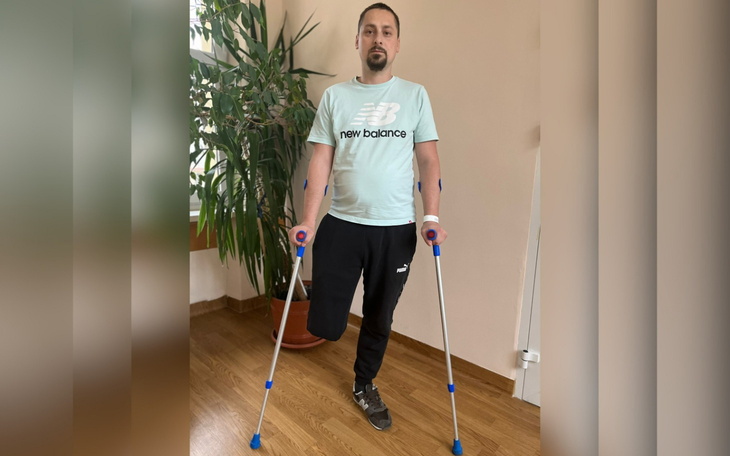 Mężczyzna na kulach, z opatrunkiem na ręce.