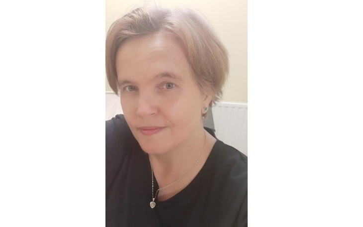 Kobieta z krótkimi włosami, uśmiechająca się do kamery.