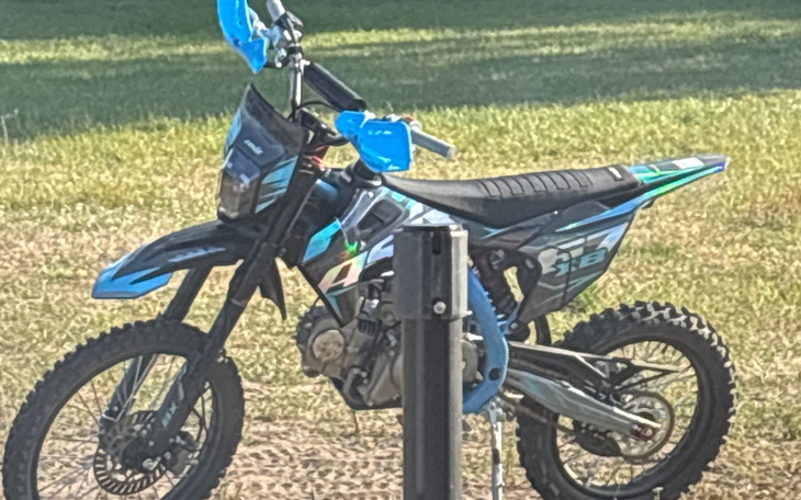 Motocykl terenowy zaparkowany na trawie.