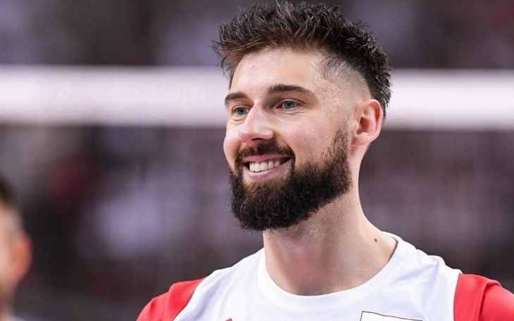 Uśmiechnięty siatkarz w koszulce reprezentacji Polski.