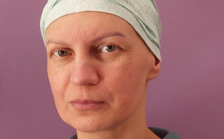 Kobieta w chustce na głowie, patrząca w kamerę.