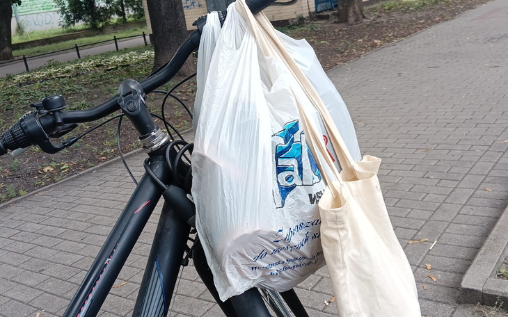 Torba na rowerze, z zakupami w plastikowej i materiałowej torbie.