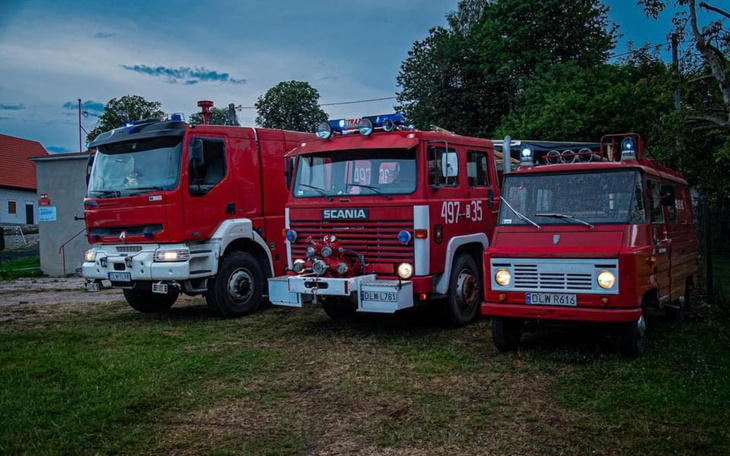 Trzy pojazdy strażackie zaparkowane na terenie.