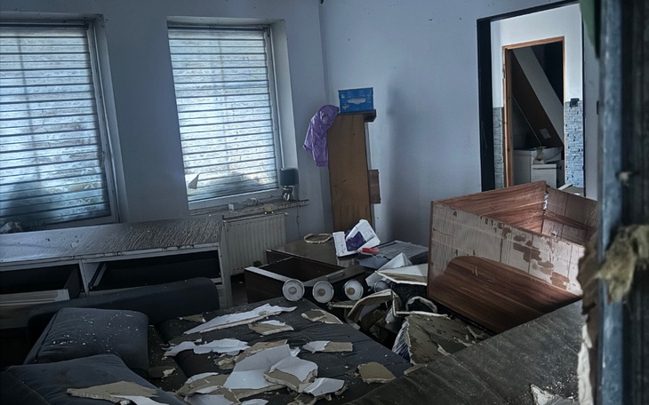 Zniszczone wnętrze pomieszczenia z meblami i bałaganem.