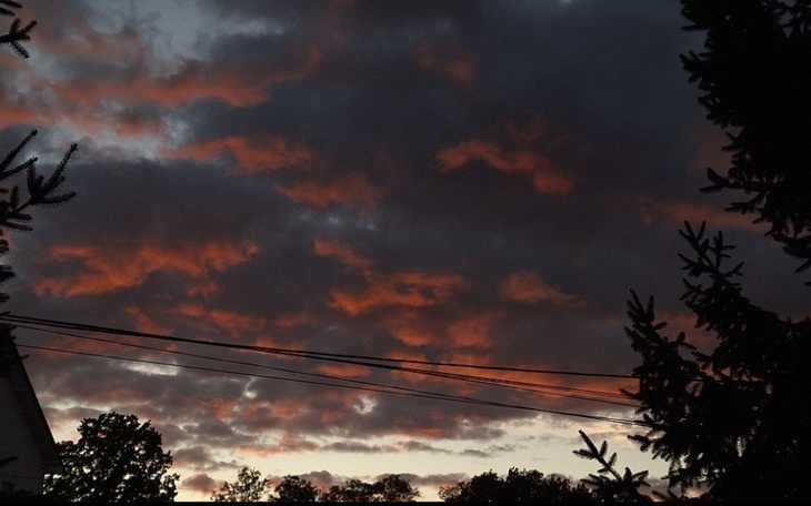 Zachód słońca z chmurami w odcieniach pomarańczowego i szarego.