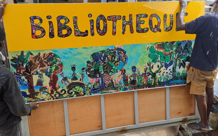 Mural przedstawiający kolorowe postacie i drzewa, z napisem 'BIBLIOTHEQUE'.