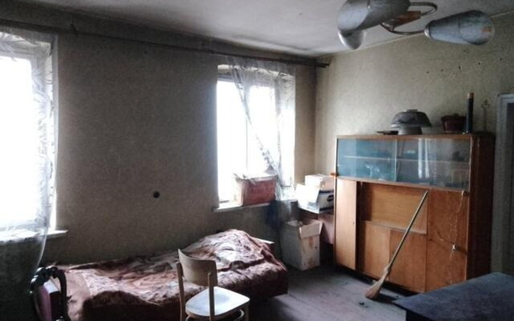 Pusty pokój z łóżkiem i meblami, z widokiem na okna.