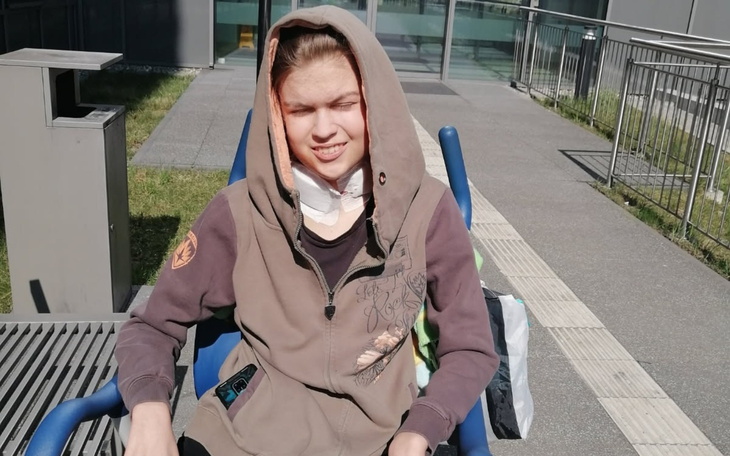 Młoda osoba w bluzie z kapturem, siedząca na wózku.