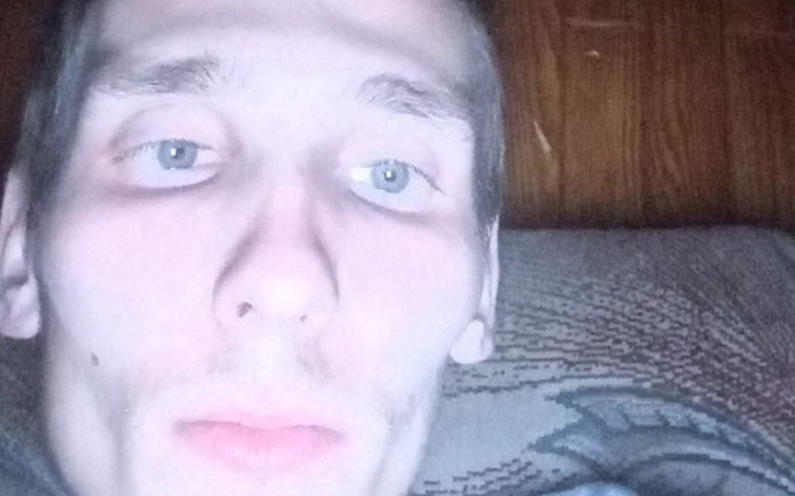 Mężczyzna z jasnymi oczami robi selfie w ciemnym pomieszczeniu.