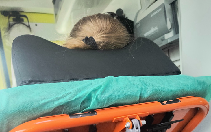 Kobieta leżąca na noszach w karetce, z głową opartą na oparciu.