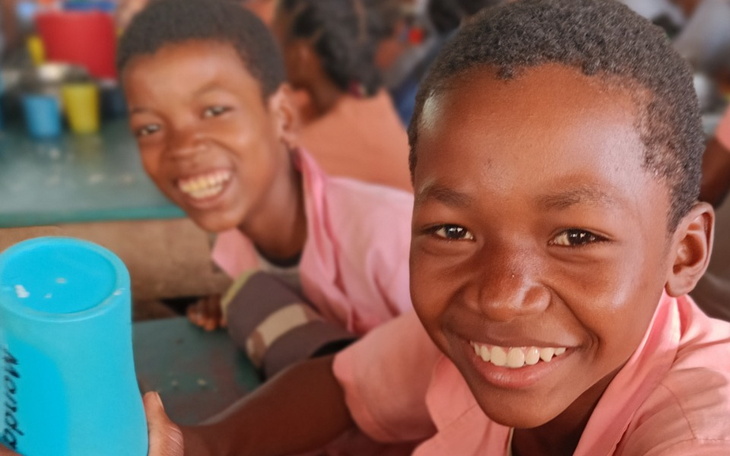 Dzieci uśmiechające się podczas posiłku w stołówce.