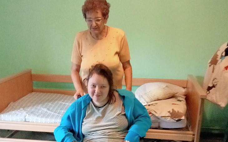 Kobieta pomagająca osobie na wózku w przytulnym pokoju.