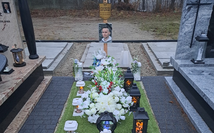 Grób z kwiatami i zniczem, z portretem na nagrobku.