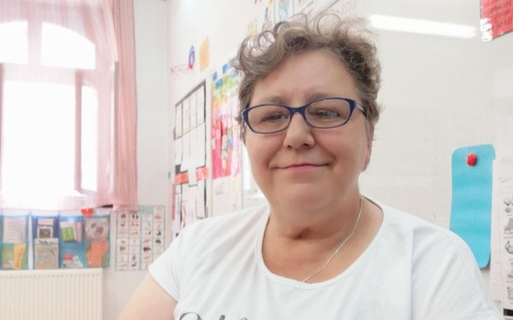 Uśmiechnięta nauczycielka w klasie, z okularami.