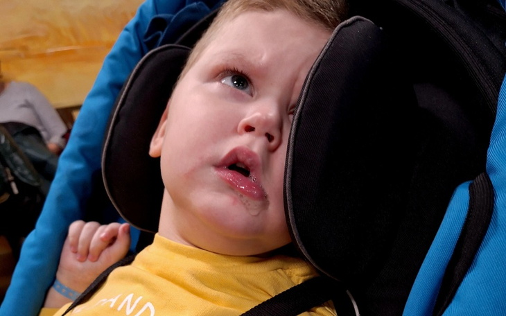 Mały chłopiec w wózku, z wyrazem twarzy pełnym emocji.