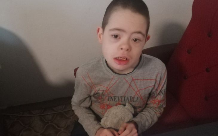 Chłopiec z zespołem Downa trzymający pluszowego misia.