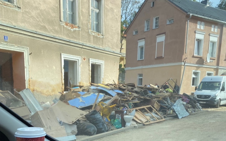 Złomowisko z odpadami budowlanymi przed budynkiem.