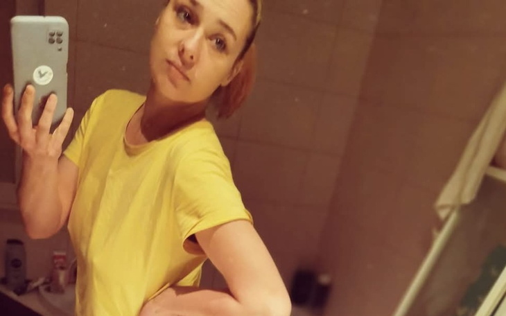 Kobieta w żółtej koszulce robiąca selfie w łazience.