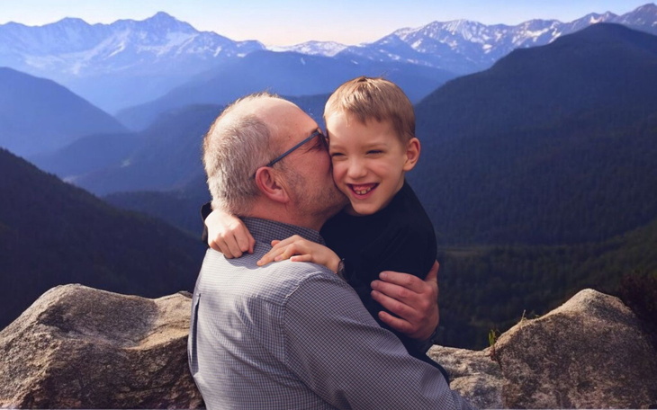 Chłopiec przytulający dziadka na tle gór.
