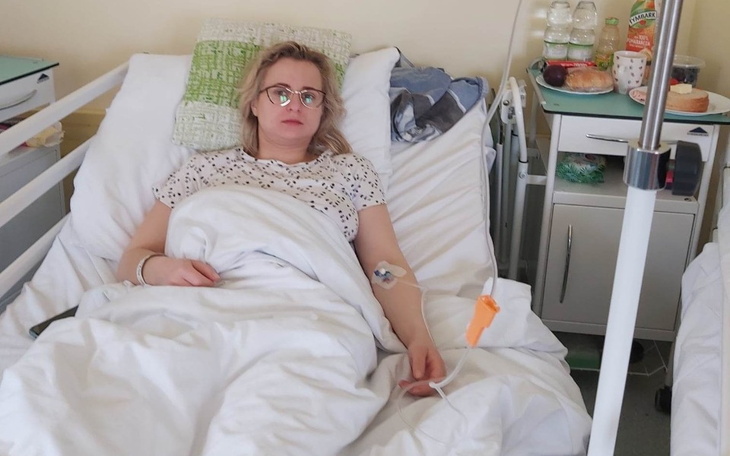 Kobieta leżąca w łóżku szpitalnym, wygląda na zmęczoną.