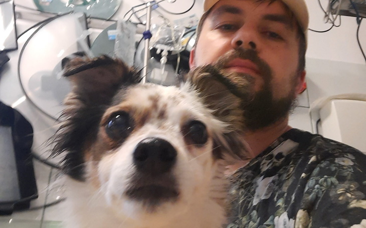 Mężczyzna z psem, selfie w przytulnym otoczeniu.