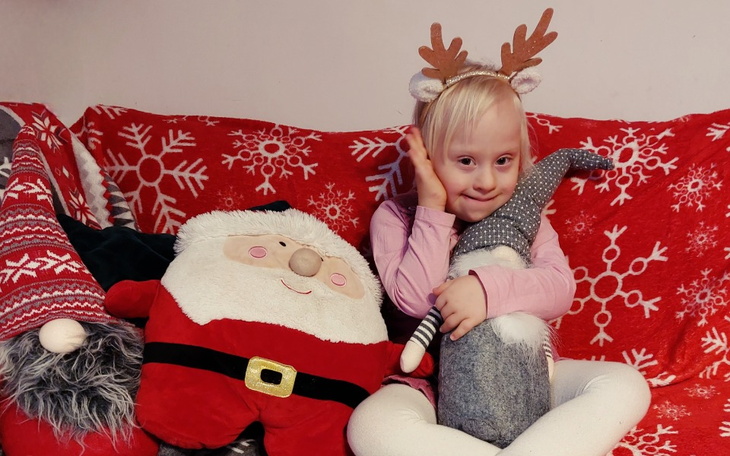 Dziewczynka w świątecznym stroju, siedząca z pluszakami.