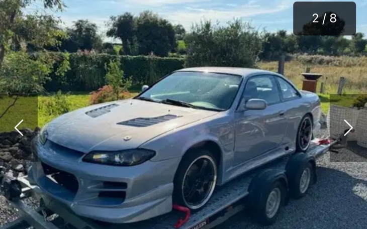 Samochód sportowy na przyczepie, gotowy do transportu.