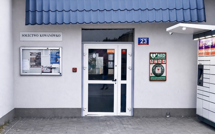 Budynek sołectwa z tablicą informacyjną i AED.