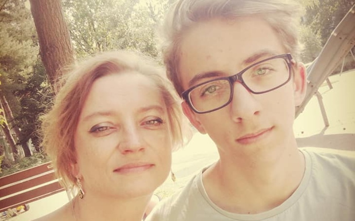 Młody chłopak z mamą, oboje uśmiechnięci w parku.