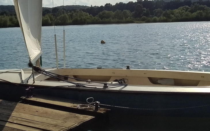Jacht cumujący przy brzegu jeziora.