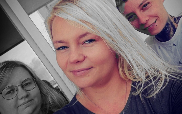 Trzy osoby pozujące do zdjęcia, uśmiechnięte na tle okna.