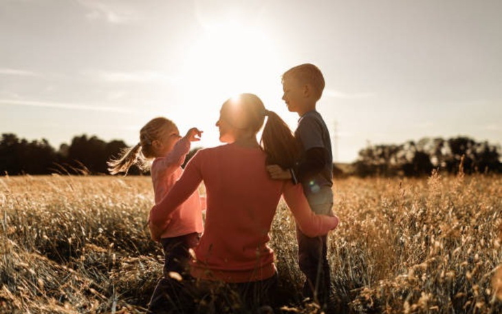 Rodzina cieszy się wspólnym czasem na tle zachodzącego słońca.