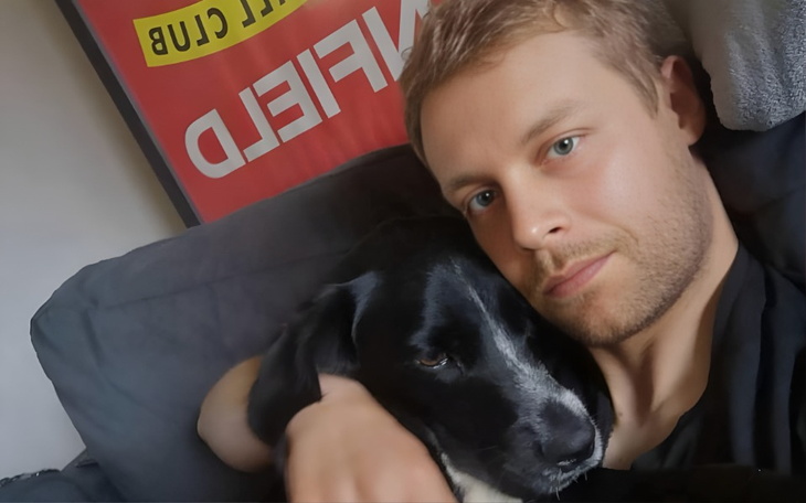 Mężczyzna przytula psa na kanapie, obaj wyglądają na szczęśliwych.