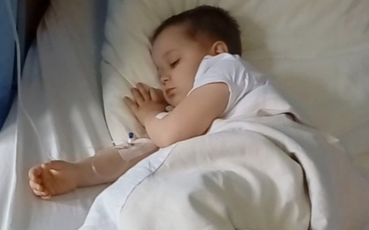 Mały chłopiec śpiący w łóżku, z kroplówką.