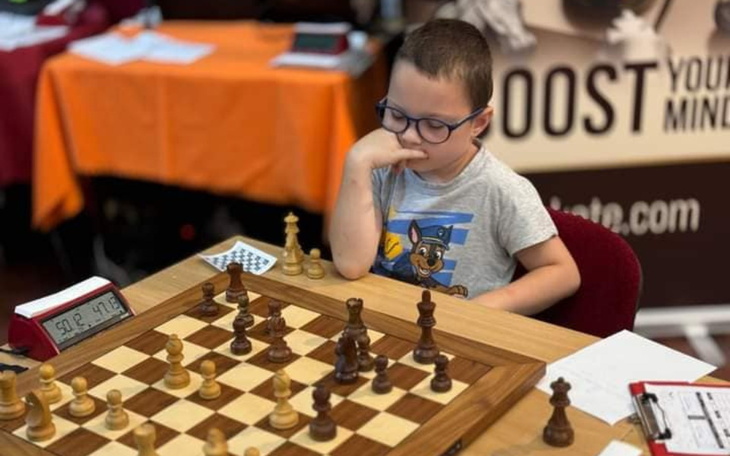 Chłopiec grający w szachy, skupiony na planszy.