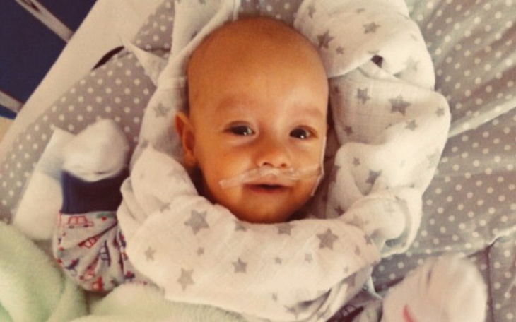 Uśmiechnięty chłopczyk w szarej pościeli.