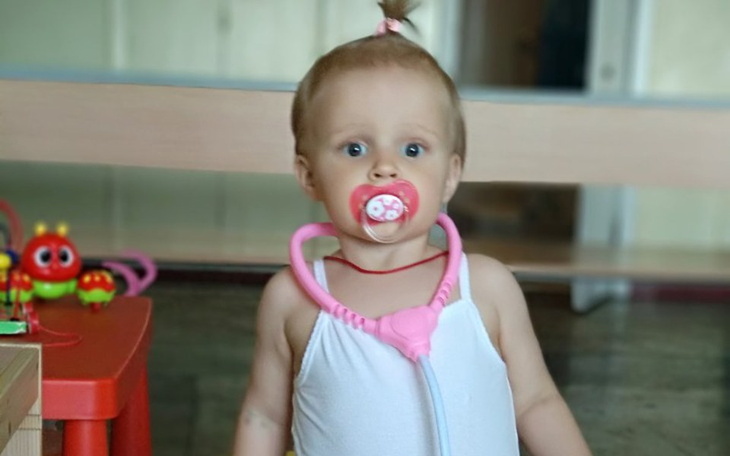 Mała dziewczynka z smoczkiem, udająca lekarza z zabawkowym stetoskopem.