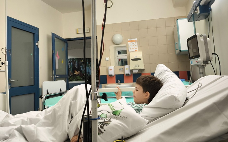 Chłopiec leży w szpitalnym łóżku, korzystając z telefonu.