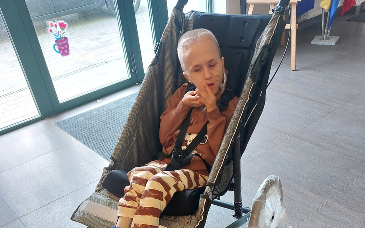 Chłopiec w wózku, gestykulujący w pomieszczeniu.