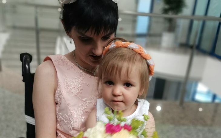 Kobieta trzymająca dziecko, obie uśmiechnięte.