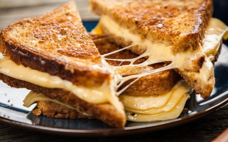 Talerz z pysznymi, ciągnącymi się kanapkami z serem.