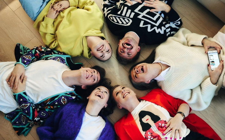 Grupa młodych ludzi leżących w kręgu, uśmiechających się i cieszących chwilą.