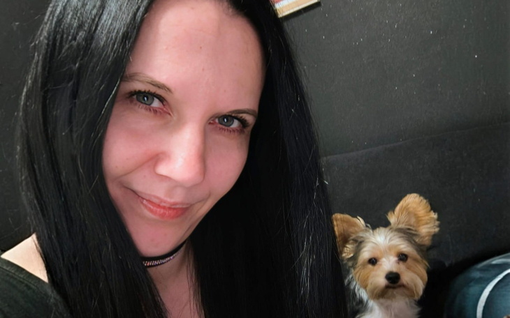 Portret kobiety z psem, uśmiechnięta i zrelaksowana.